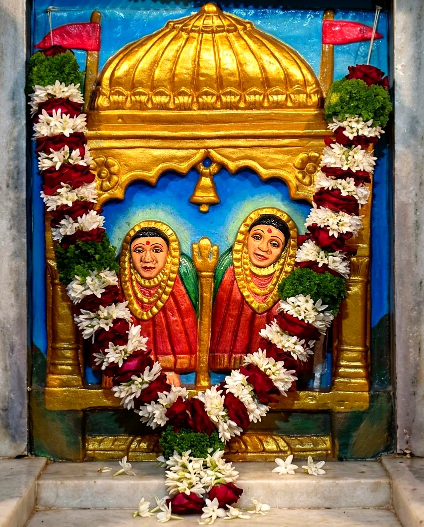 Garlanded relief of the two Devis beneath a golden dome, in the mandir sanctum